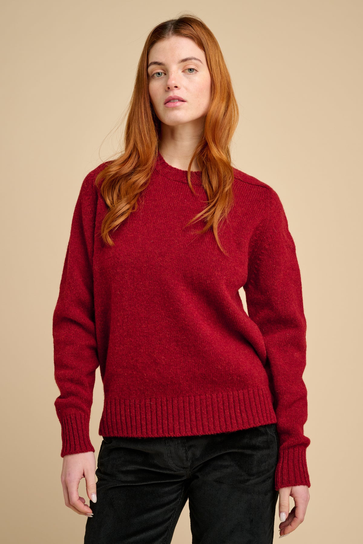 Person wearing a red sweater against a beige background