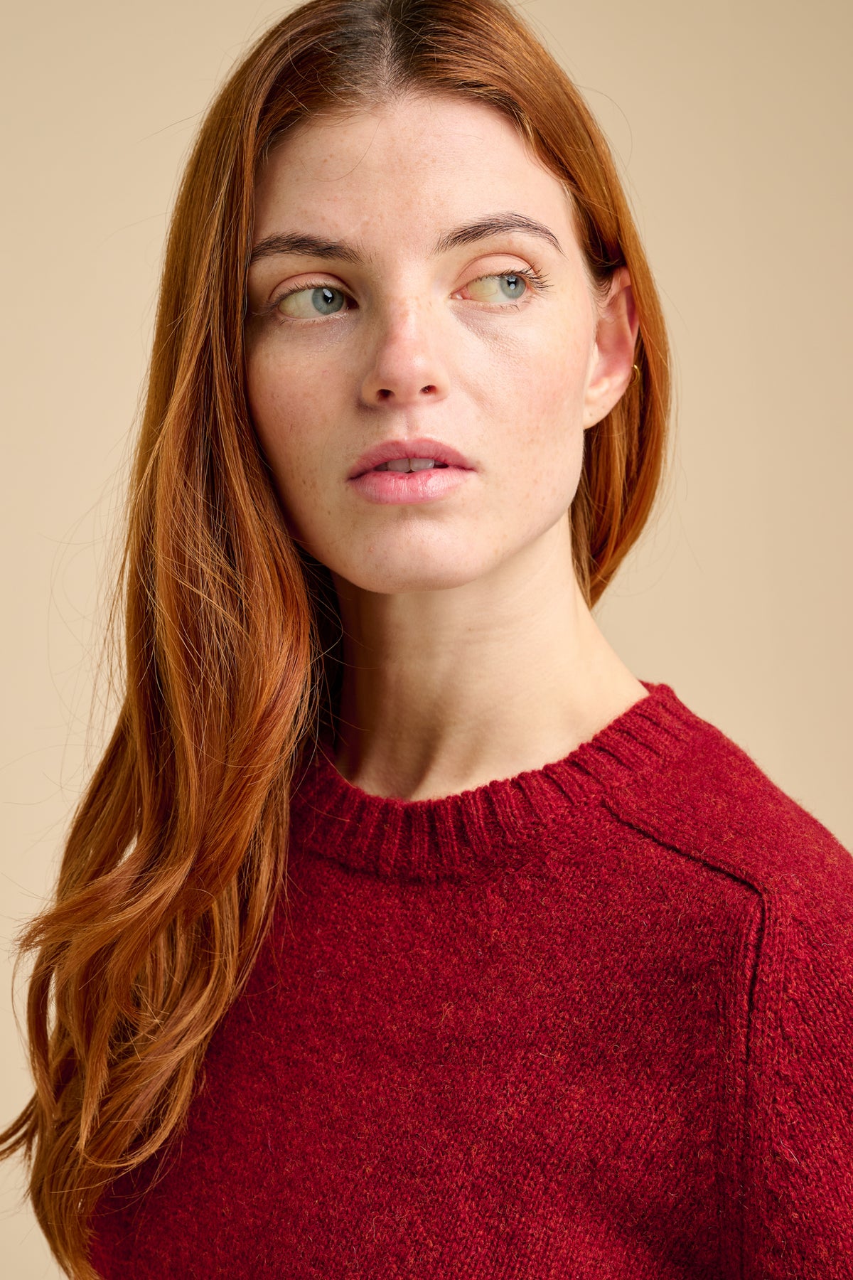 Woman wearing a red sweater against a beige background