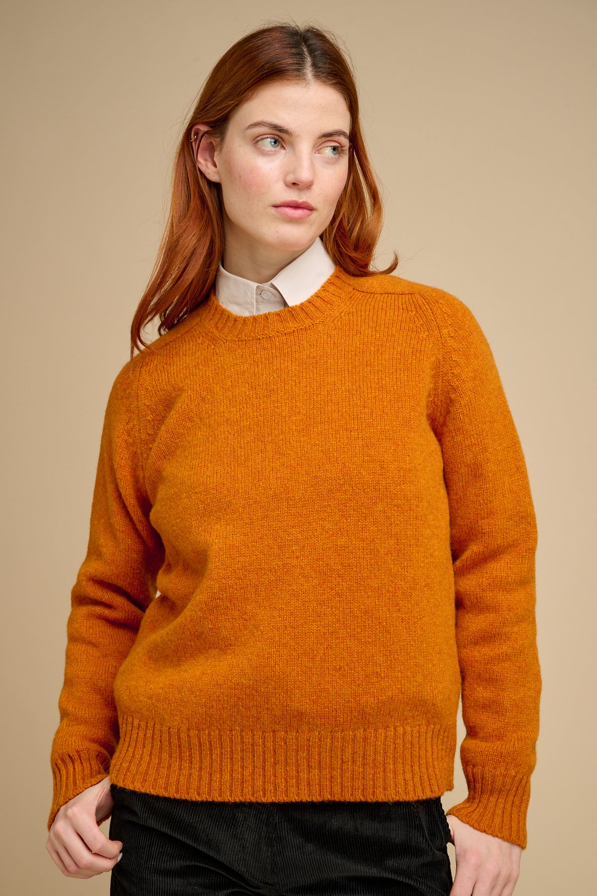 Woman wearing an orange sweater against a beige background