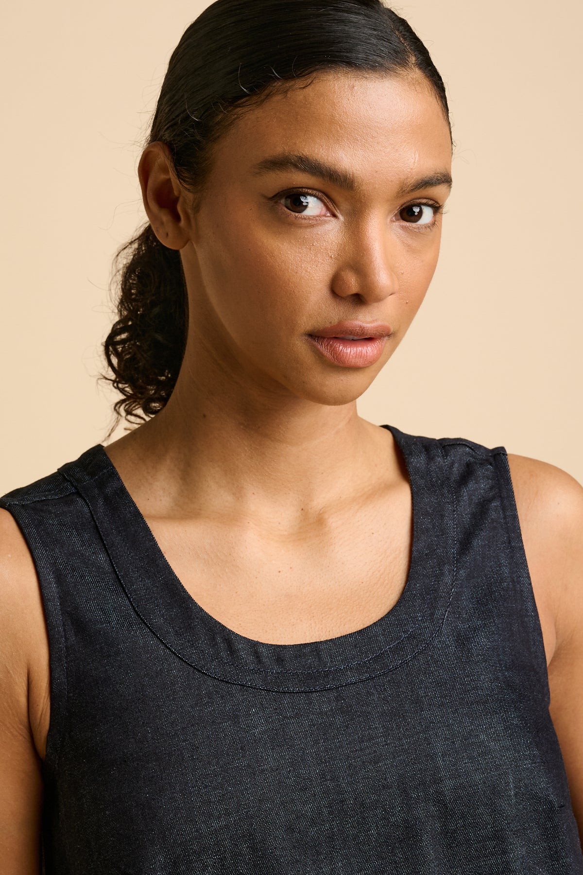 Woman wearing a indigo sleeveless dress against a beige background.