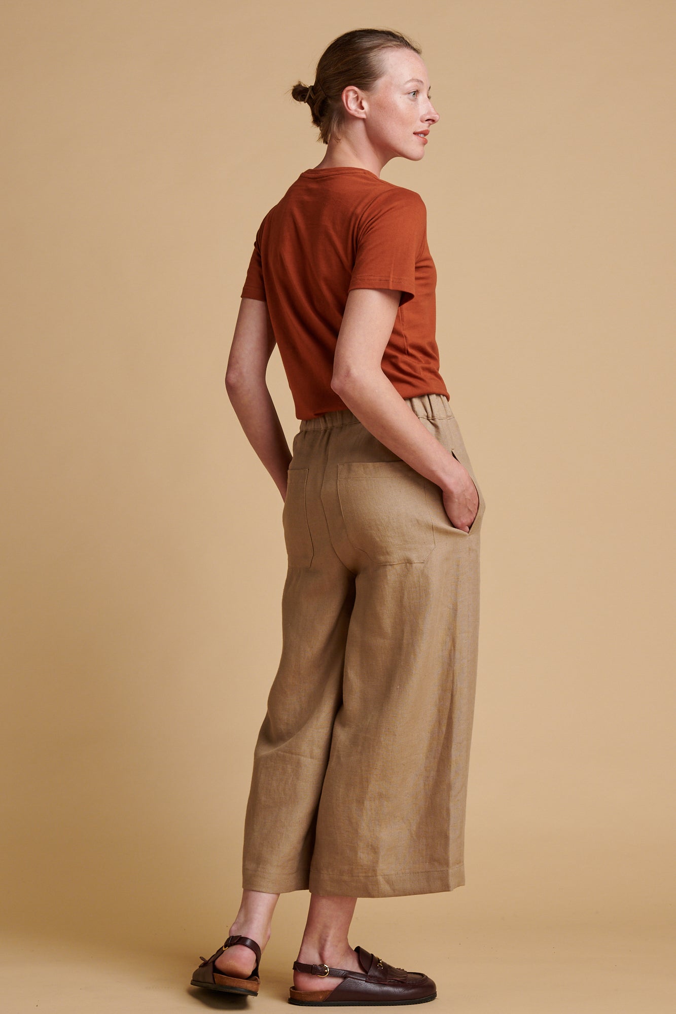Female wearing short pj trousers in truffle linen paired with short sleeve crew neck t shirt in cinnamon.