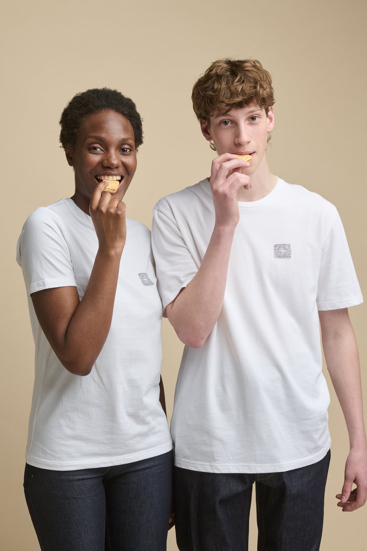 Thigh up image of female and male young models wearing short sleeve white t shirts with graphic print of custard cream line drawing on the chest