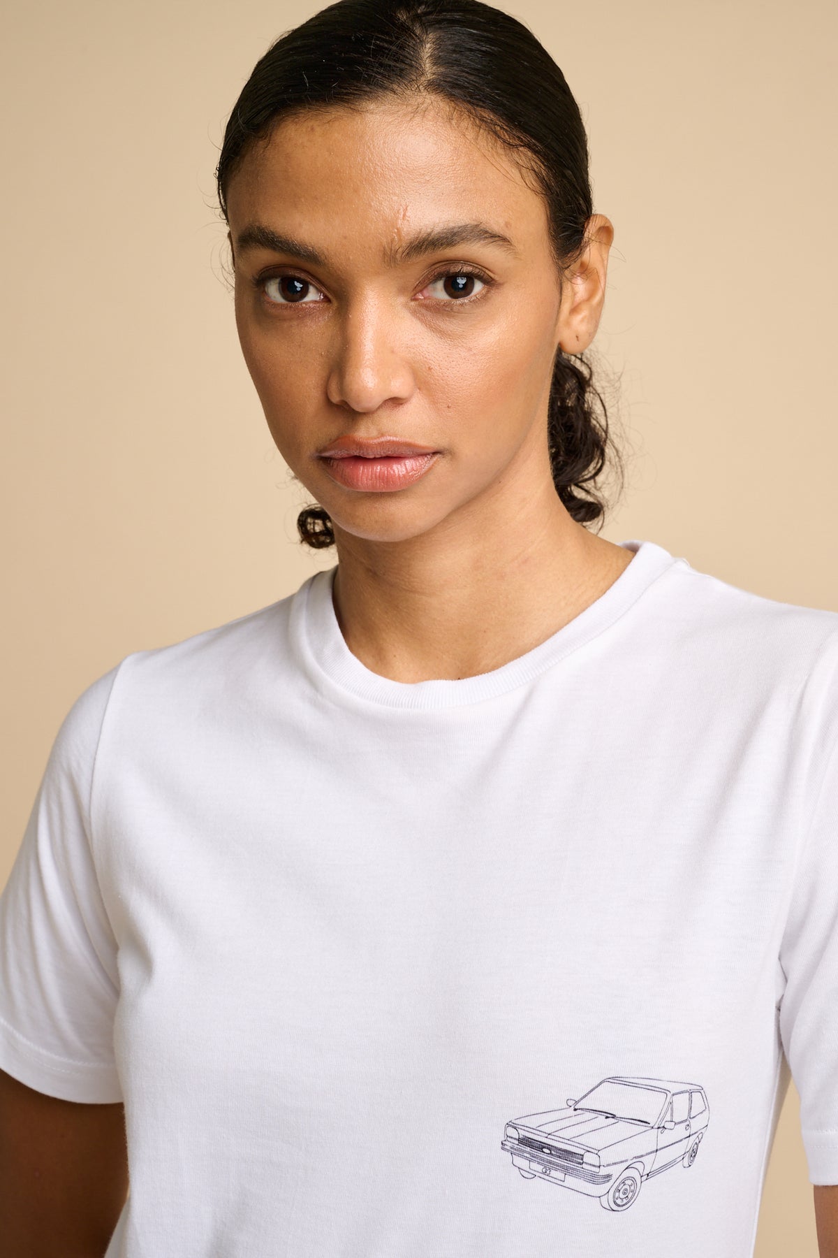 Woman wearing a white t-shirt with a car graphic print.