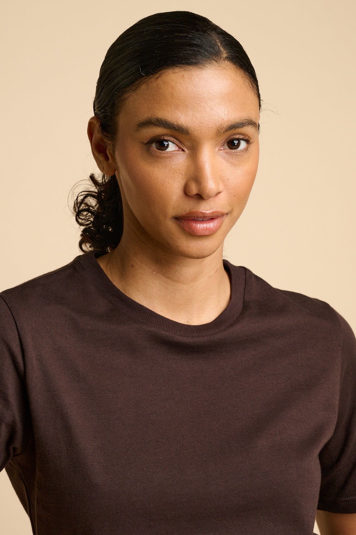 Woman wearing a brown t-shirt against a beige background