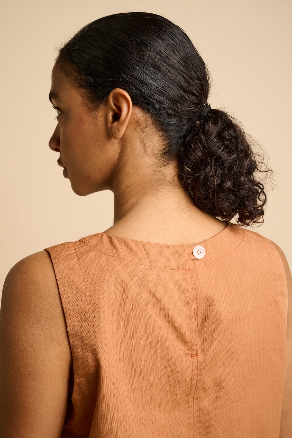 Woman wearing sleeveless orange top.