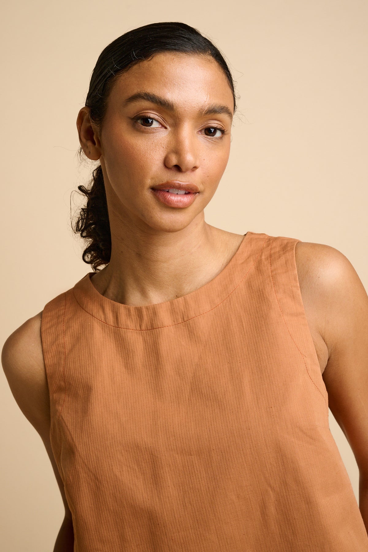 Woman wearing sleeveless orange top.
