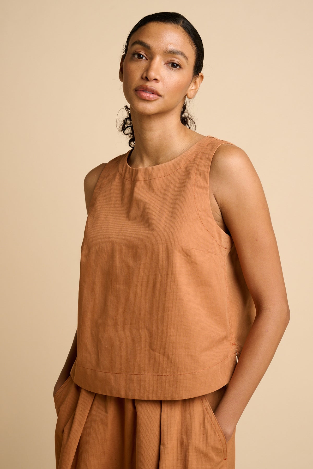 Woman wearing sleeveless orange top.