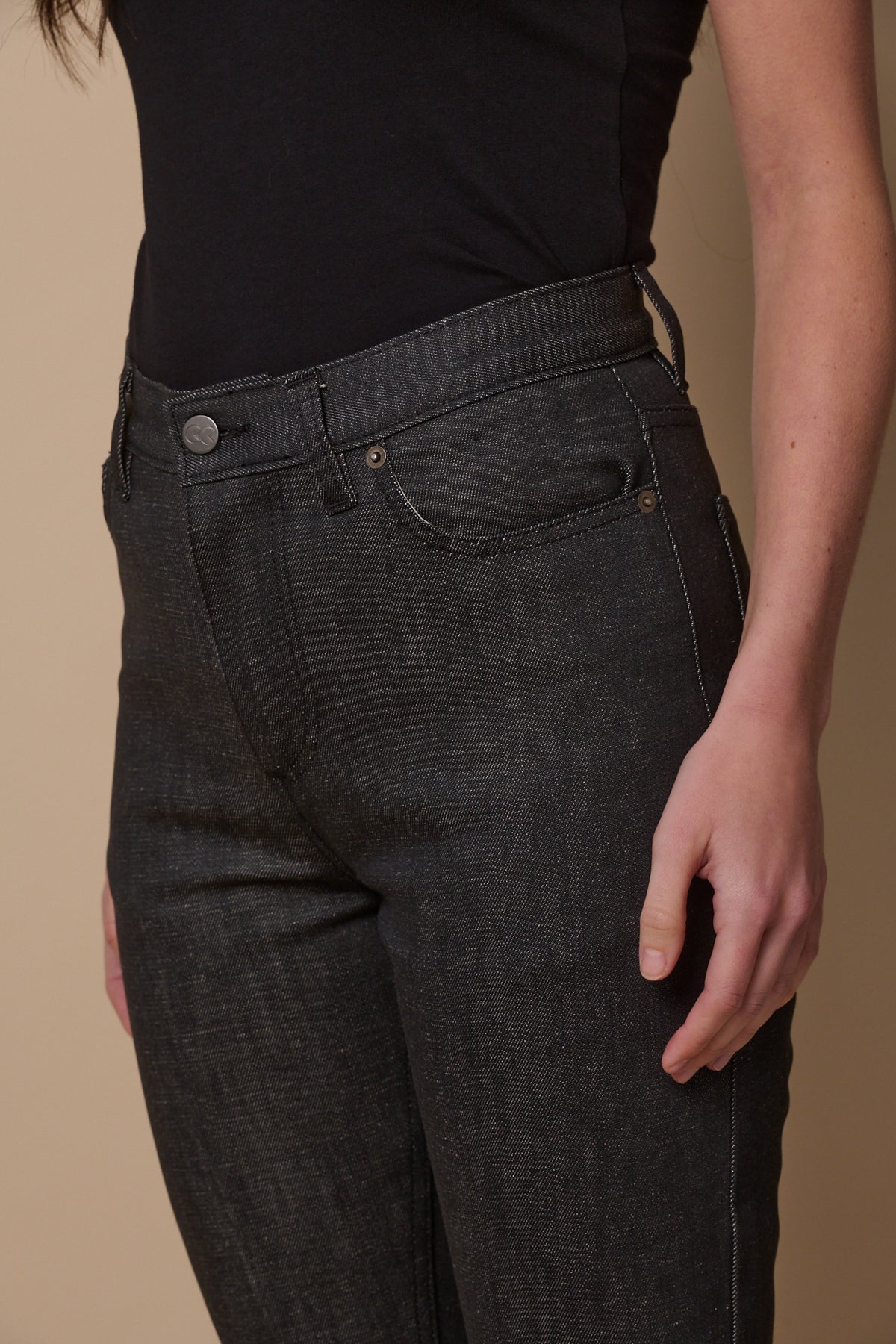 Close up image of female wearing straight leg high rise jeans in black with front  pockets and belt loops