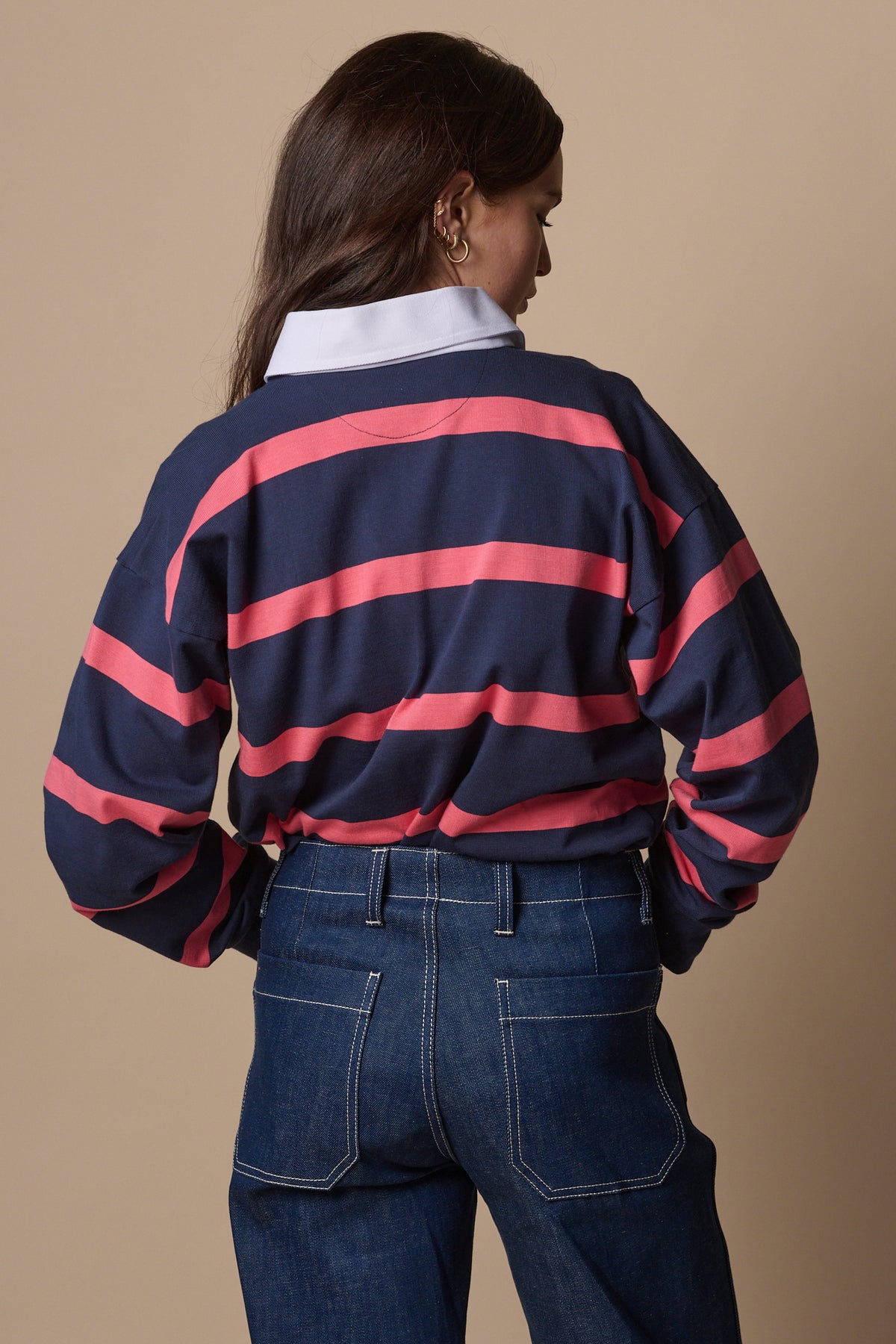 Back of female wearing striped rugby shirt in navy pink