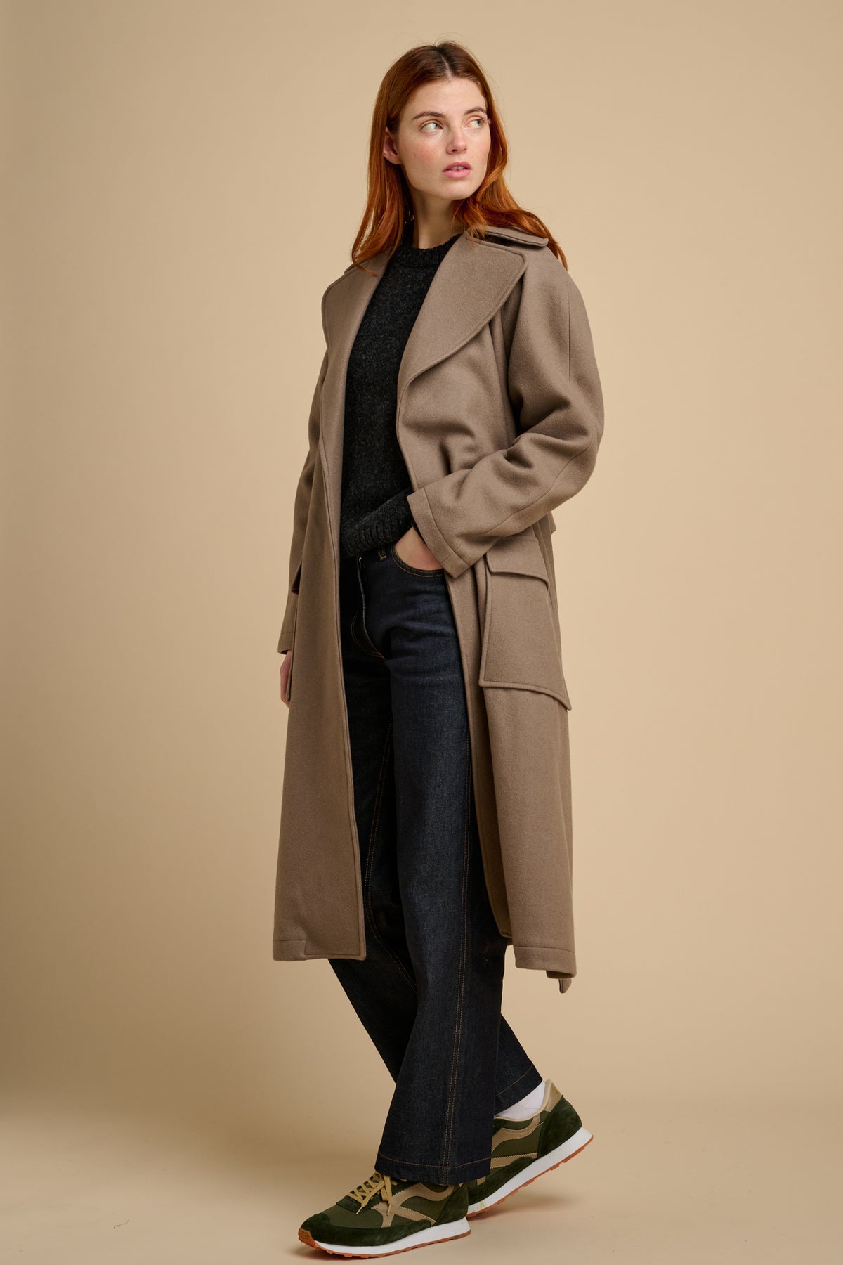 Woman wearing a beige long wool coat against a beige background