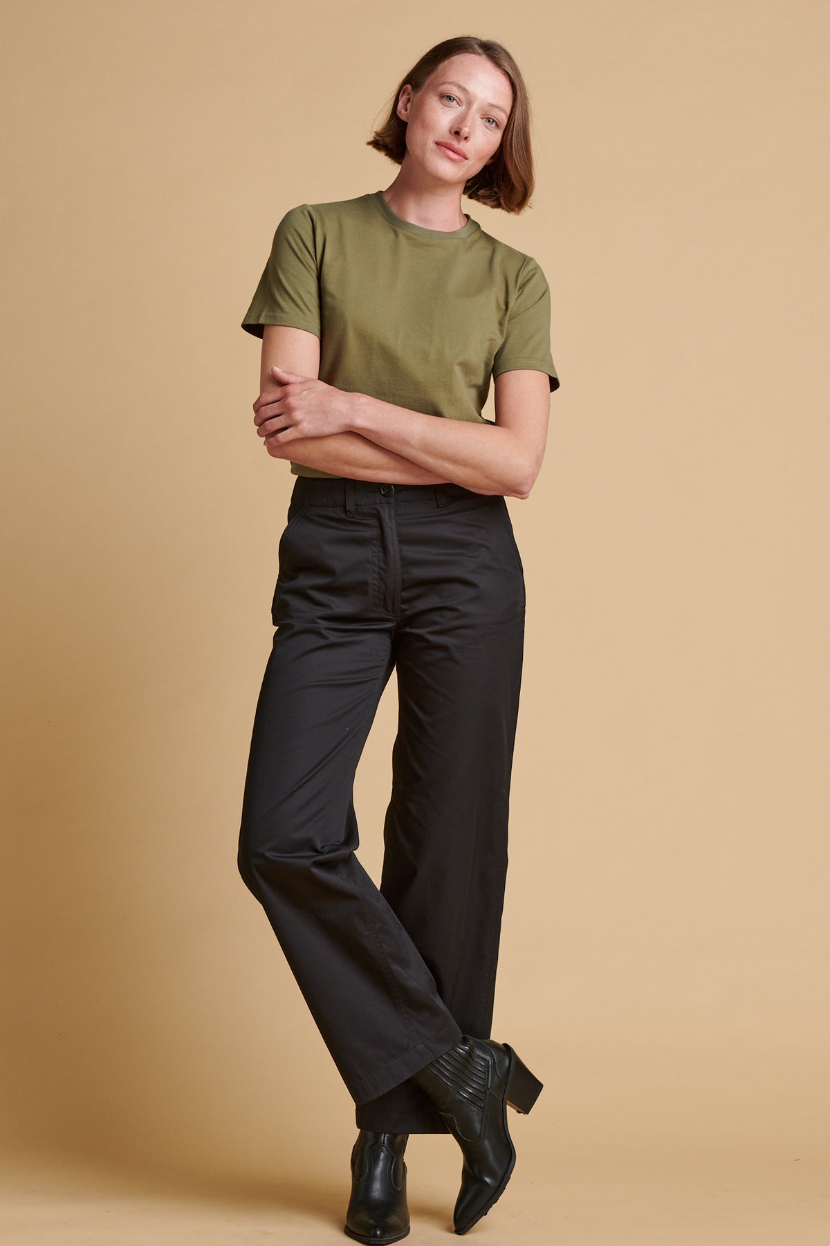 Female wearing lightweight work trousers in black paired with short sleeve t shirt in olive.