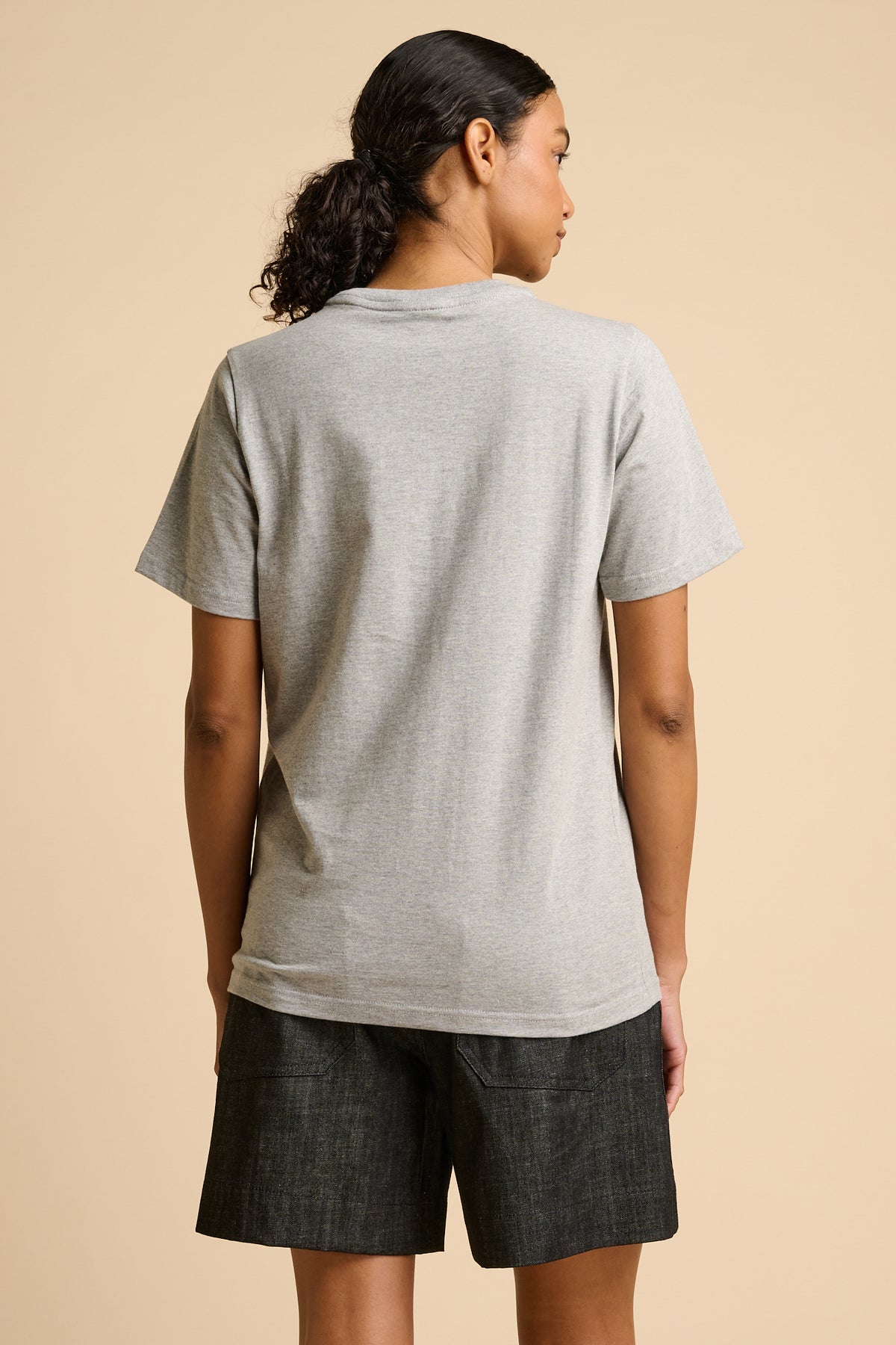 Person wearing a grey t-shirt and black shorts on a beige background.