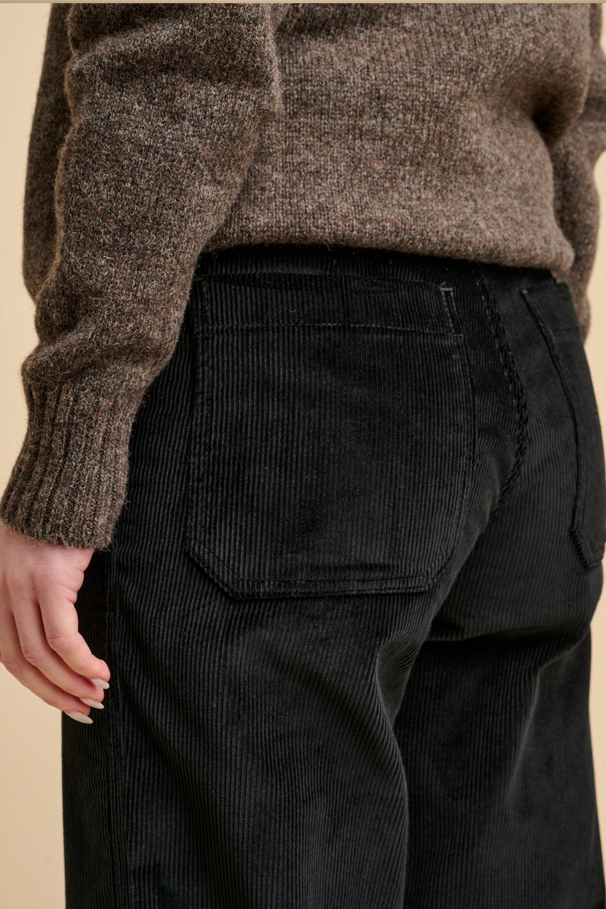 Close up of the back of woman wearing corduroy trousers with two back pockets.