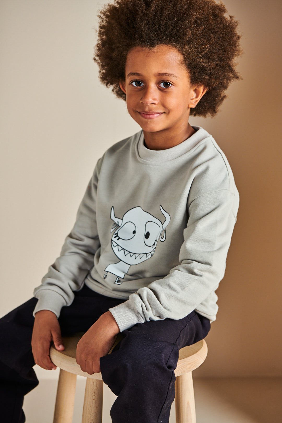 Boy wearing plastic free sweatshirt in stone with Grunhilda print on front