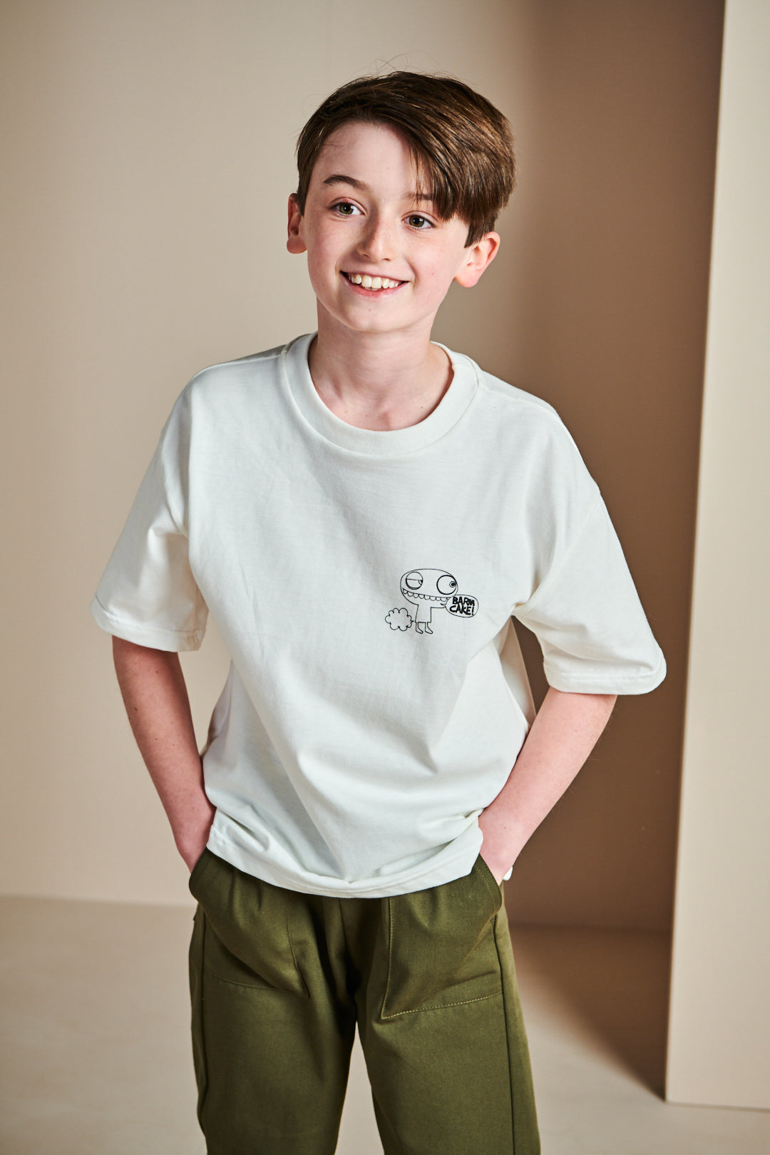 Smiley young boy wearing short sleeve t shirt in bone with barm cake! print on chest