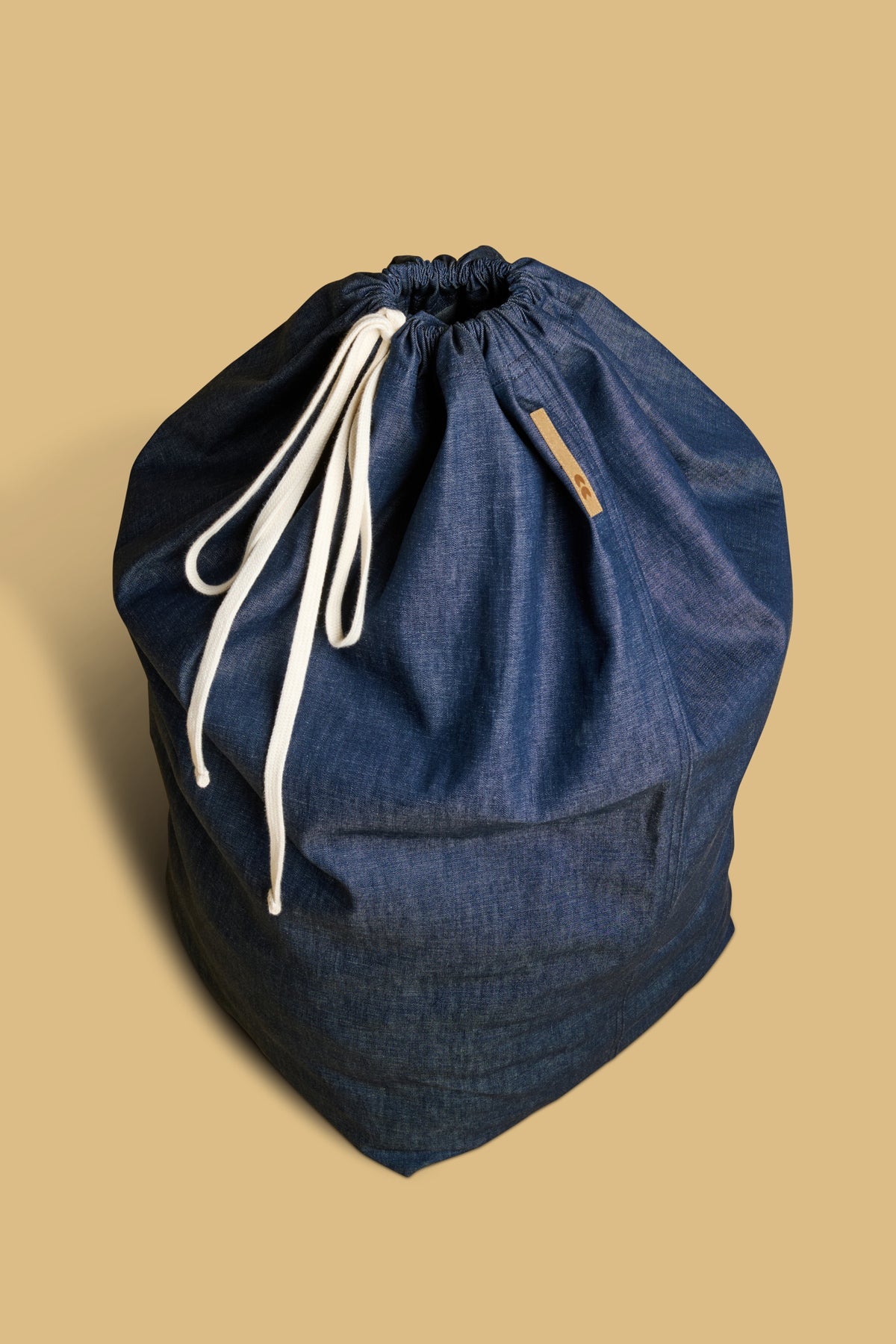 Landry bag made from deadstock indigo denim with ecru drawcord tied in a bow with CC logo patch 