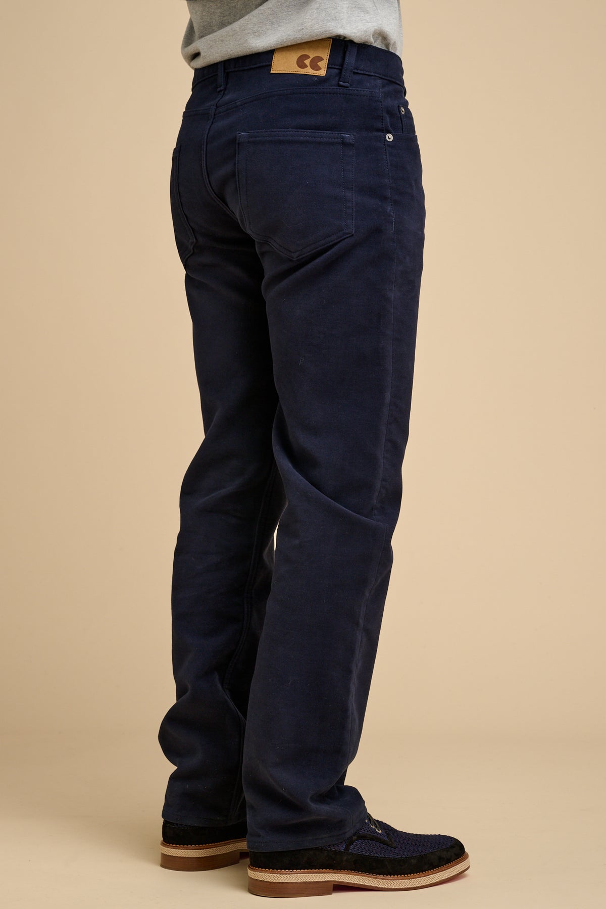 The back of male navy wearing moleskin jeans on beige background.