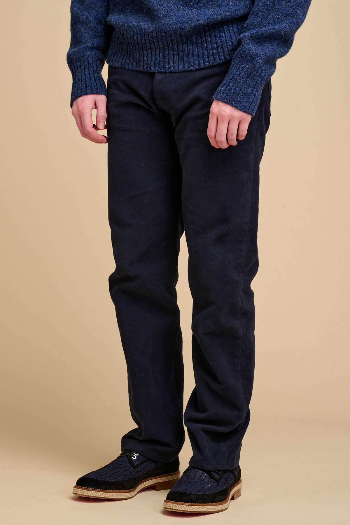 Male navy wearing moleskin jeans on beige background.