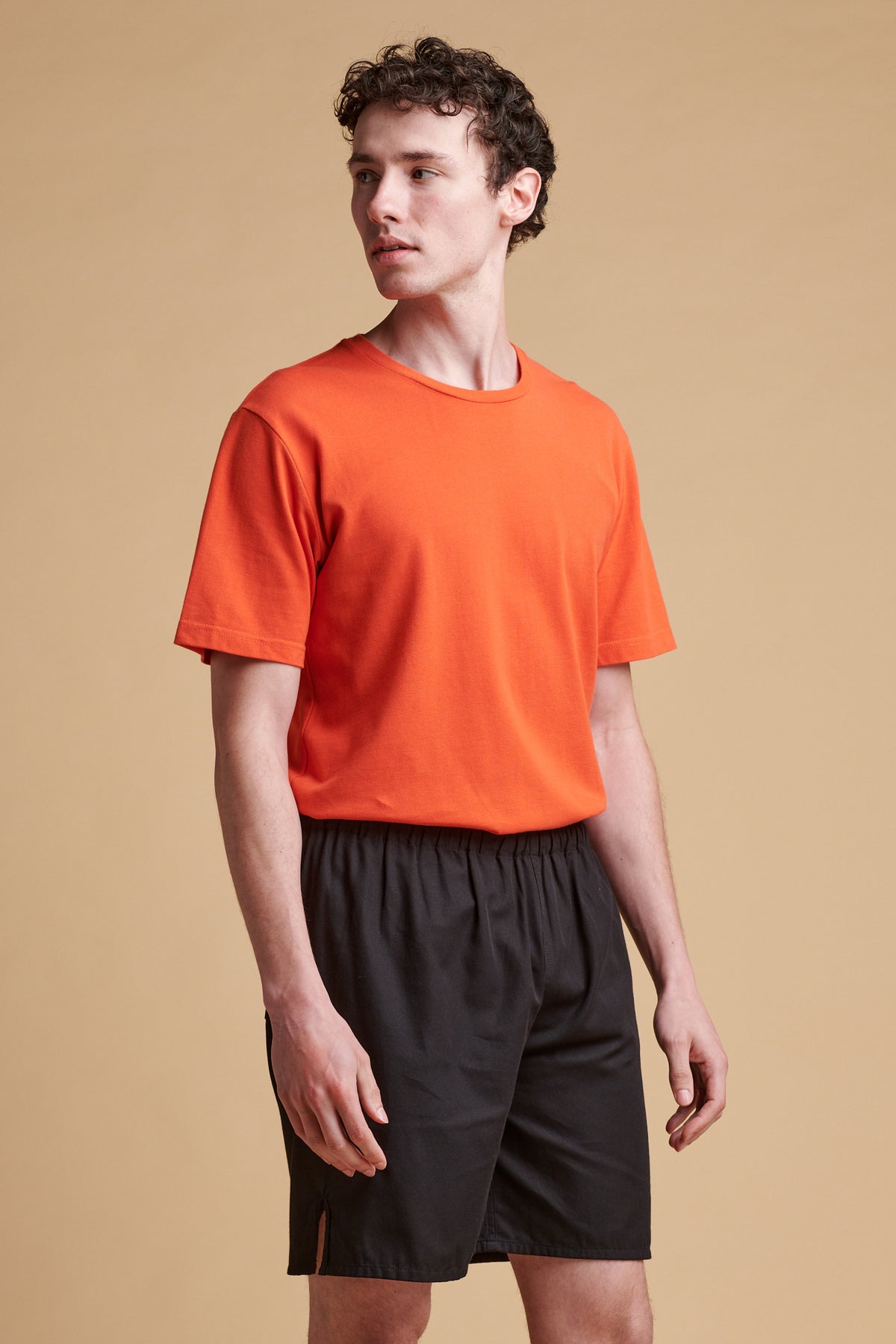 Female wearing breathable t shirt in flame red tucked into lightweight shorts.