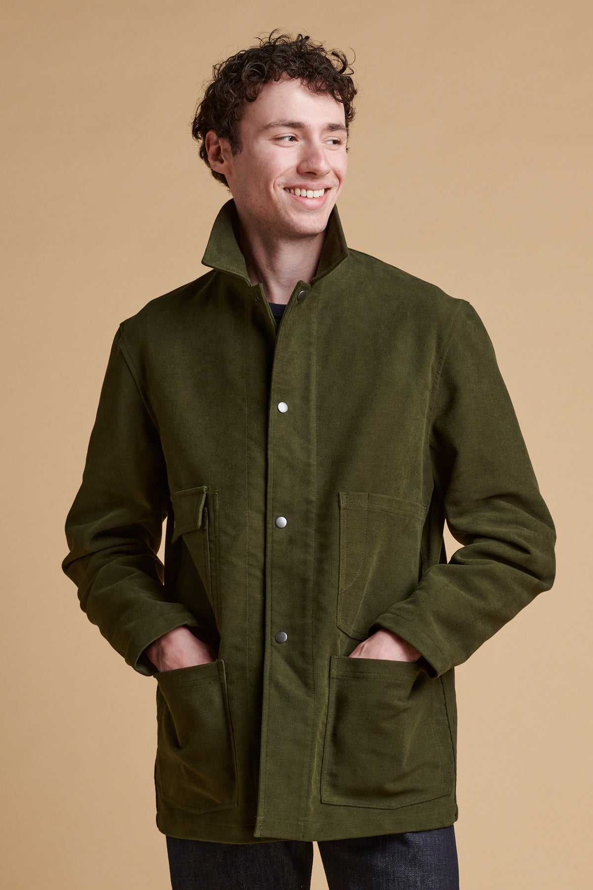 Male wearing Carter moleskin chore jacket in dark olive with collar turned up.