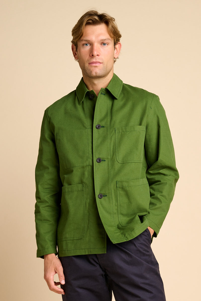 Man wearing green chore jacket against beige background.