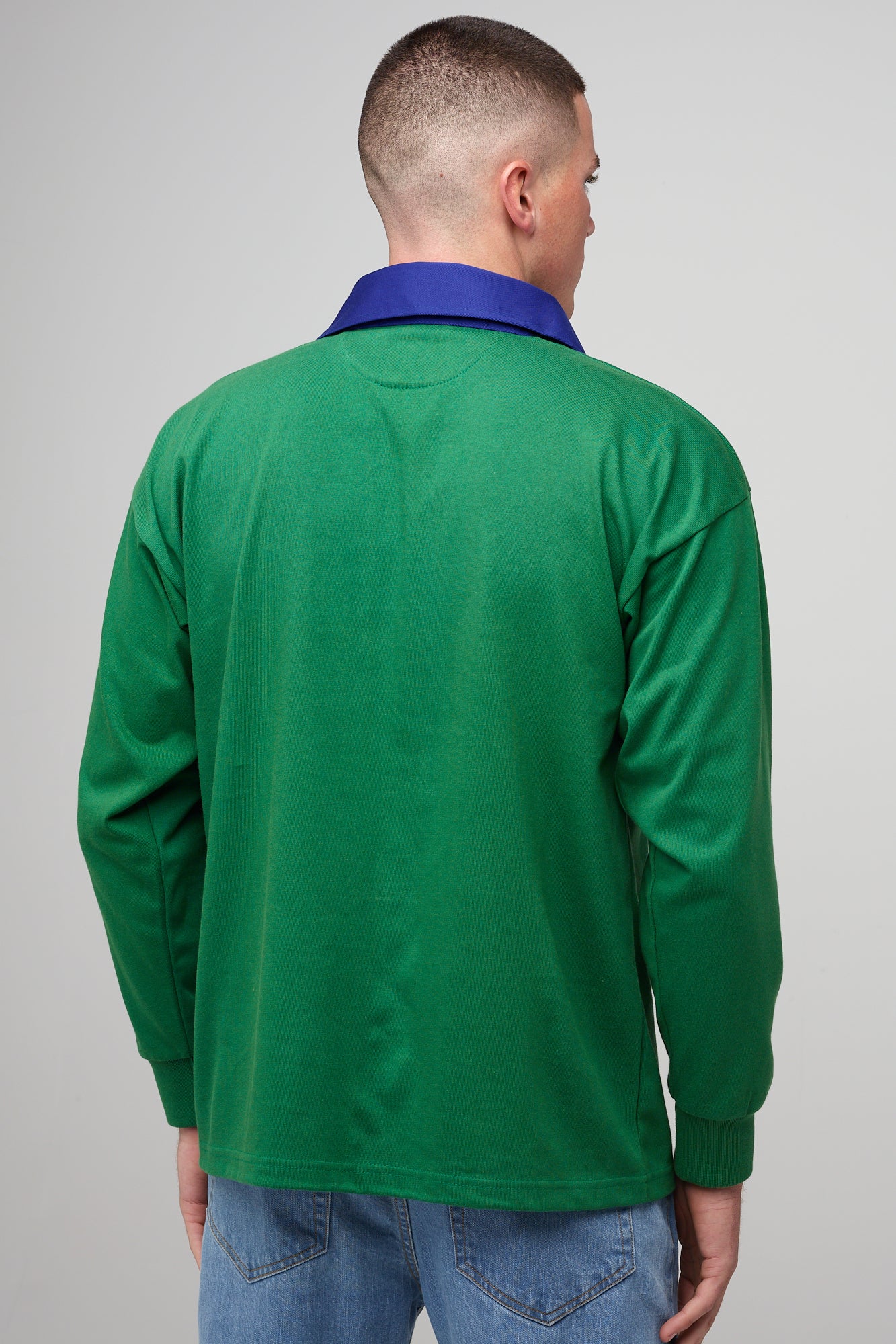 White, brunette male, wearing green rugby shirt with contrast blue collar, yellow CC logo badge 