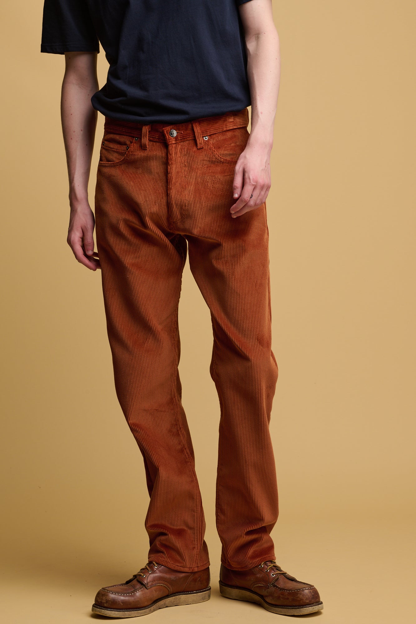 The front of male chest down wearing community clothing cord trousers in cinnamon  with CC logo silver button