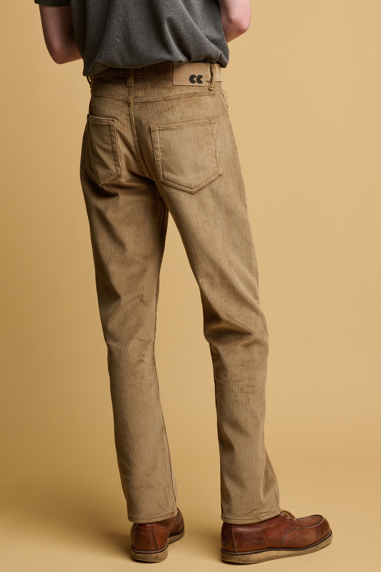 the side of male waist down wearing five pocket cord trousers in stone with brown leather shoes
