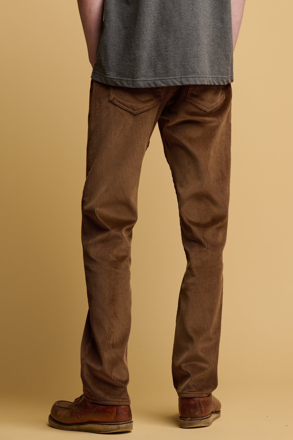 The back of male waist down wearing cord trousers in tan 