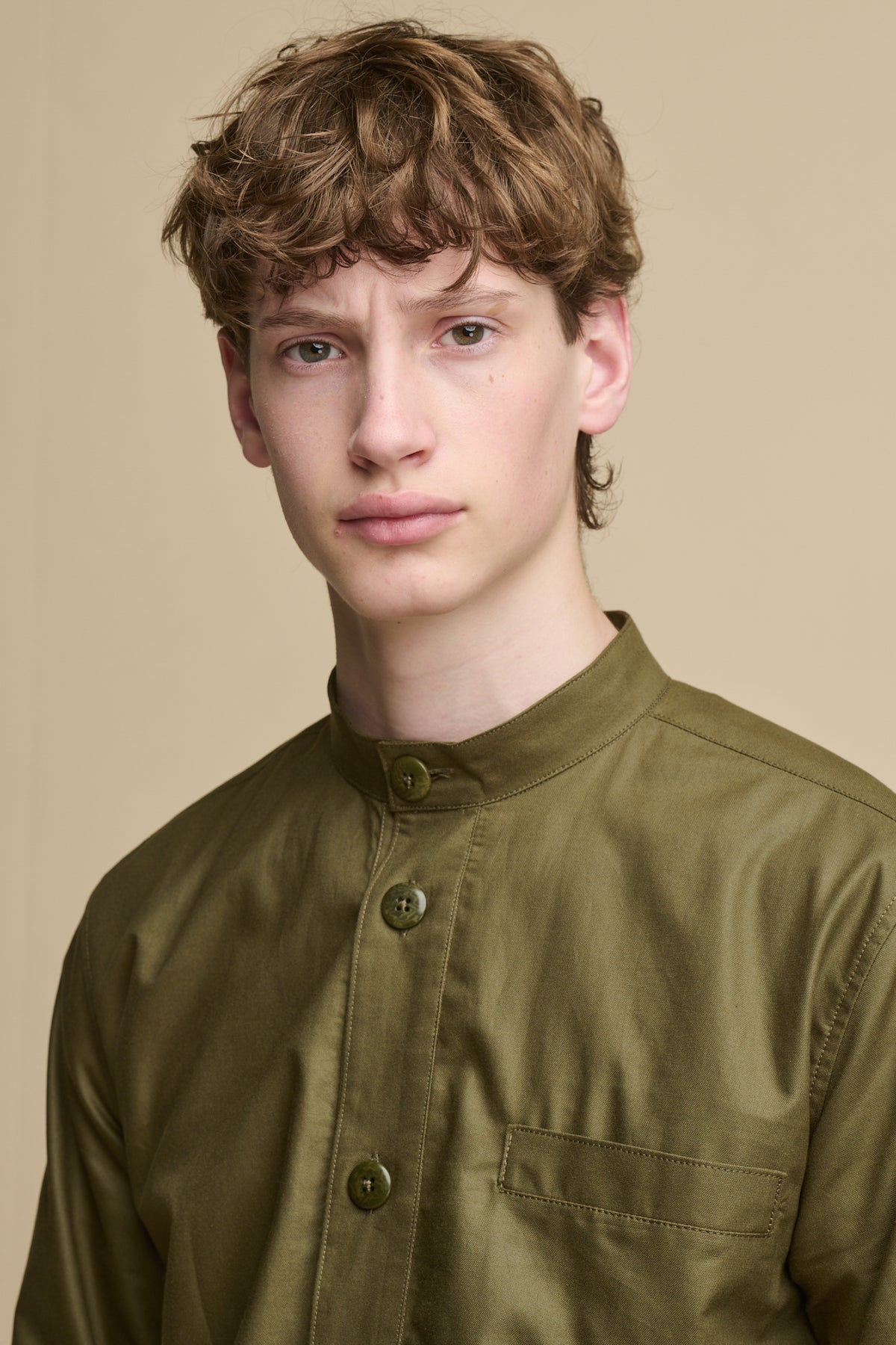 Portrait of male wearing George Lightweight Collarless Overshirt in olive with button front and pocket