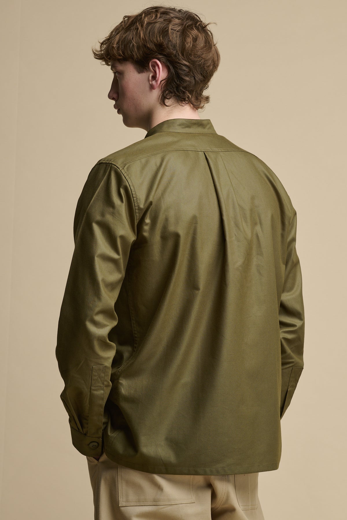 The back of men's George Lightweight Collarless Overshirt in Olive with back pleats and button fastening on cuff