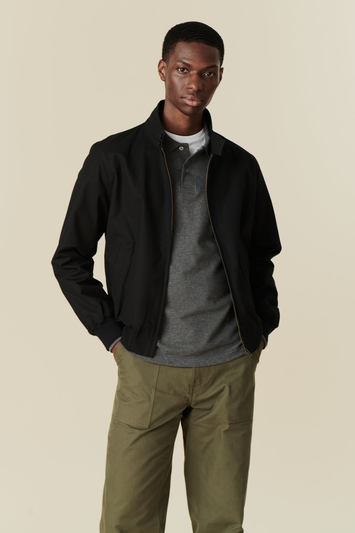 Front of black male wearing black Harrington jacket over grey long sleeve polo