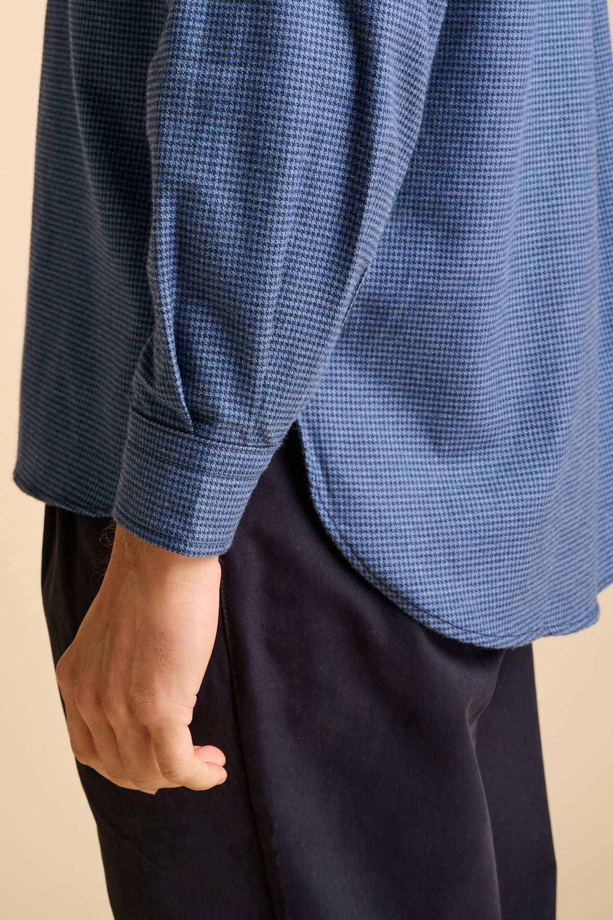 Man wearing blue shirt against beige background.