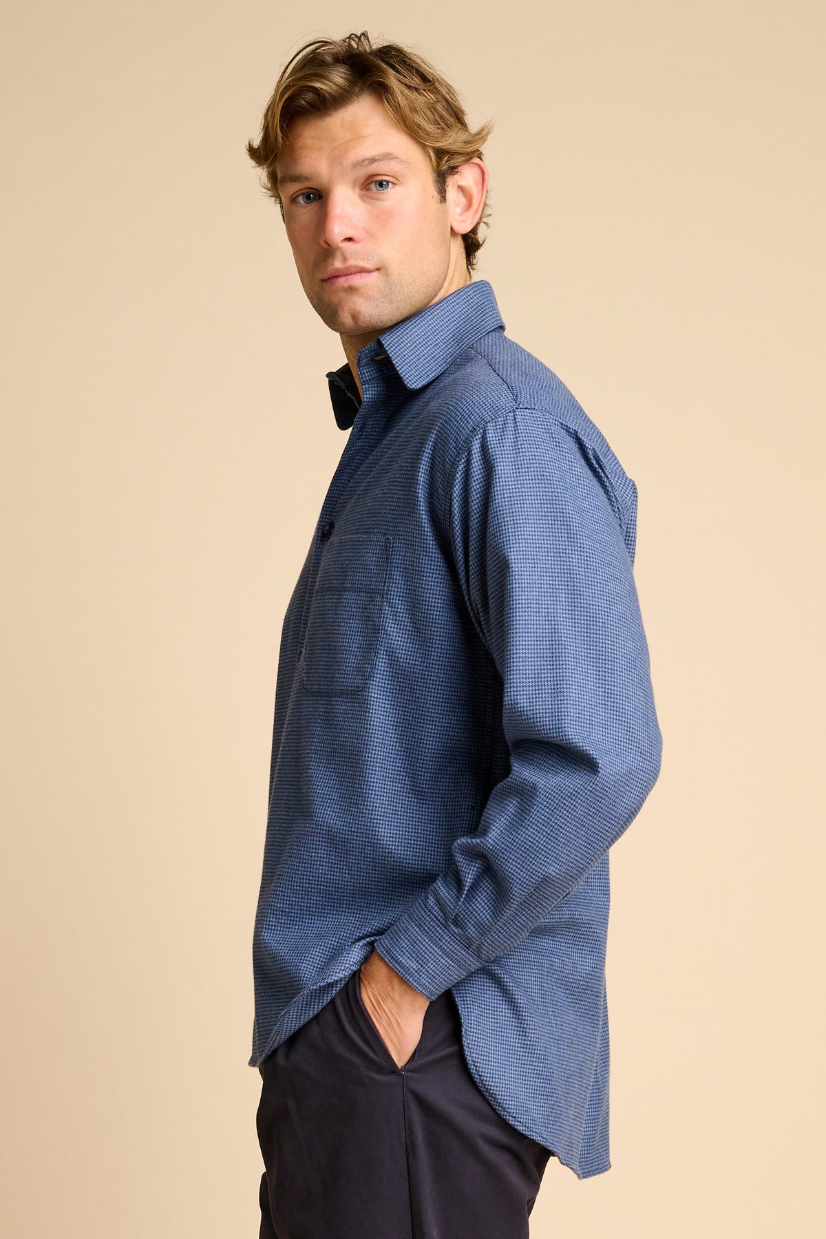 Man wearing blue shirt against beige background.