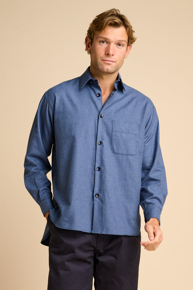 Man wearing blue shirt against beige background.