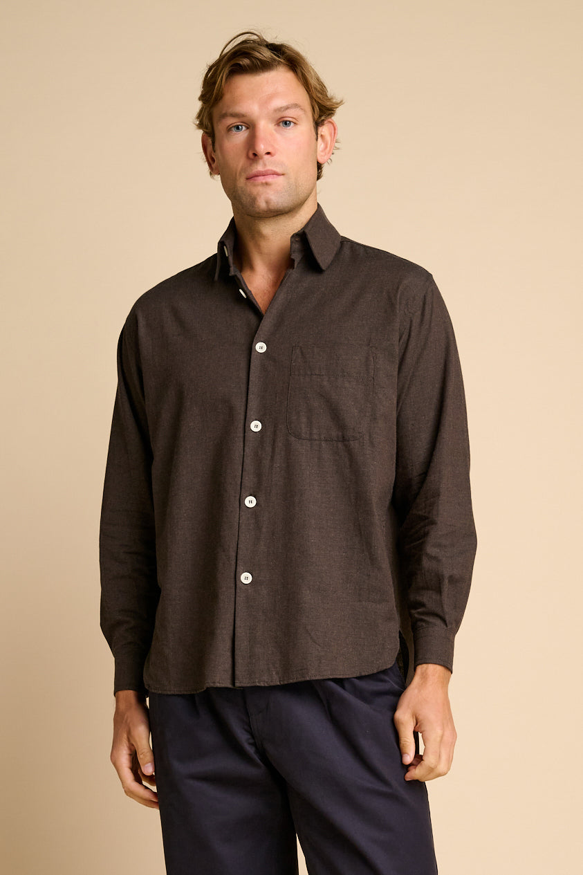 Man wearing brown shirt against beige background.