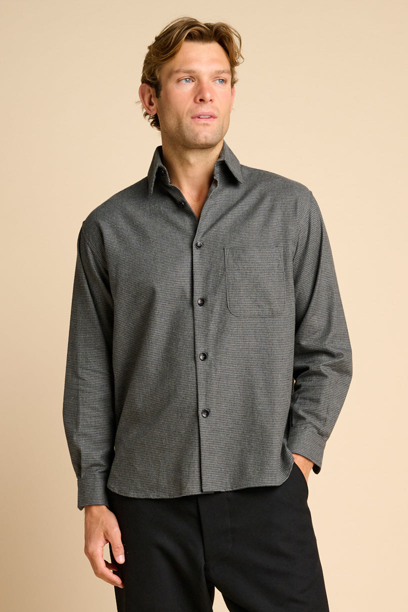 Man wearing grey shirt against beige background.