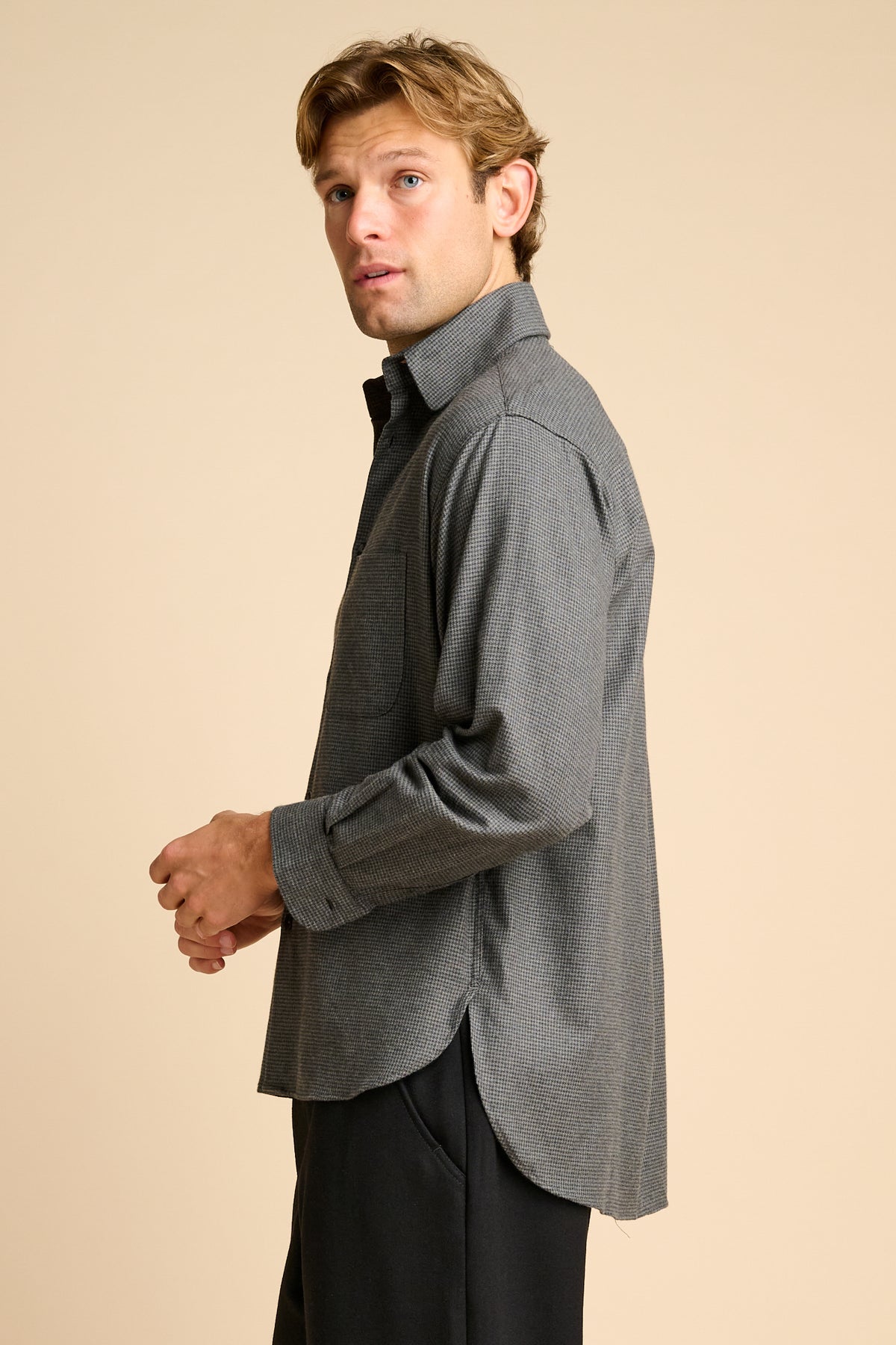 Man wearing grey shirt against beige background.