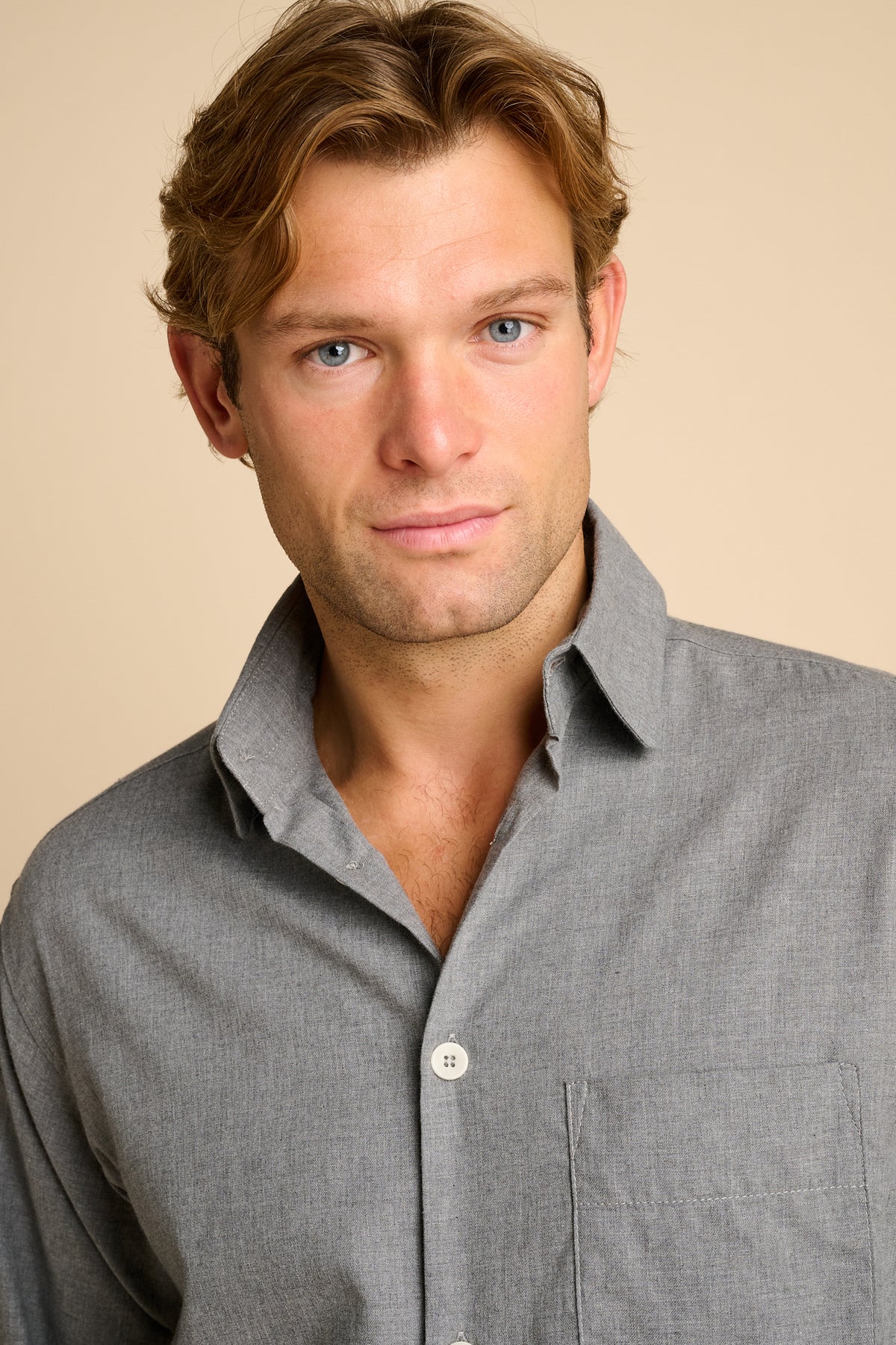 Man wearing grey shirt against beige background.