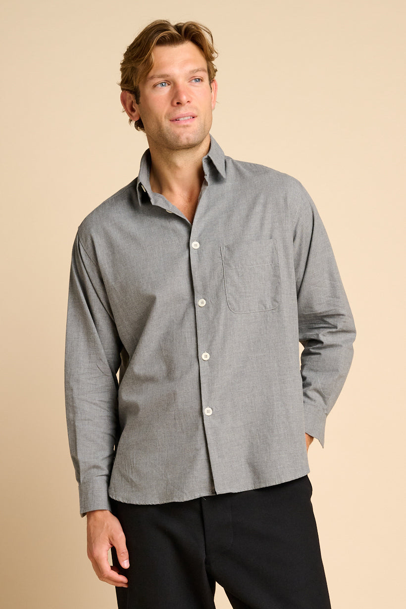 Man wearing grey shirt against beige background.