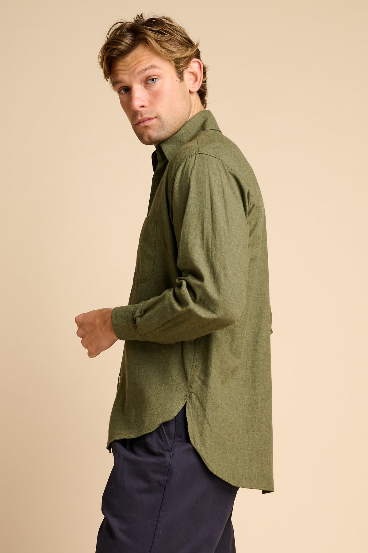 Man wearing green shirt against beige background. 