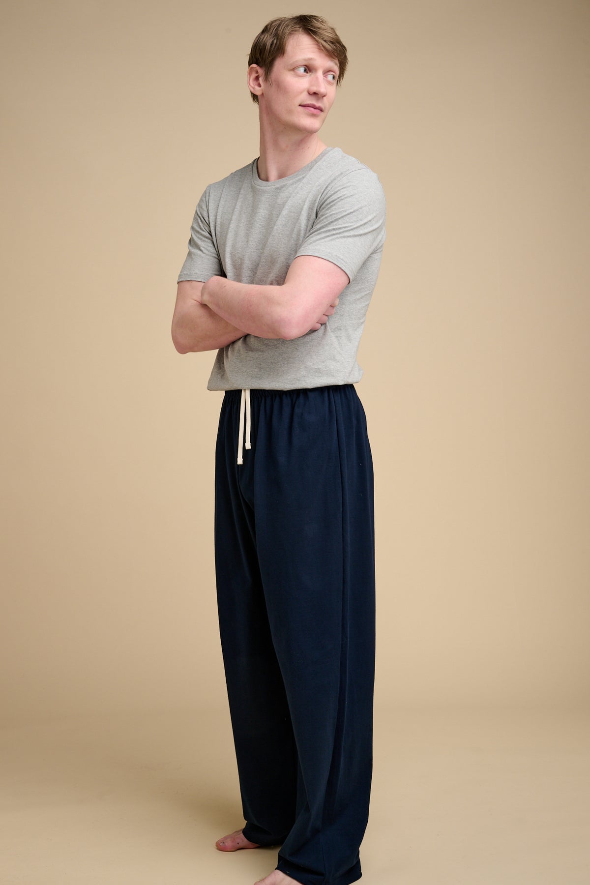 Man wearing navy pyjama bottom with grey t shirt.