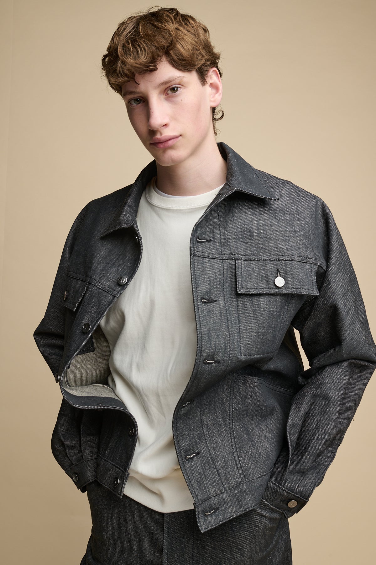 Thigh up image of male wearing Men's Joe Denim Jacket in Black worn over 80 sweatshirt in bone