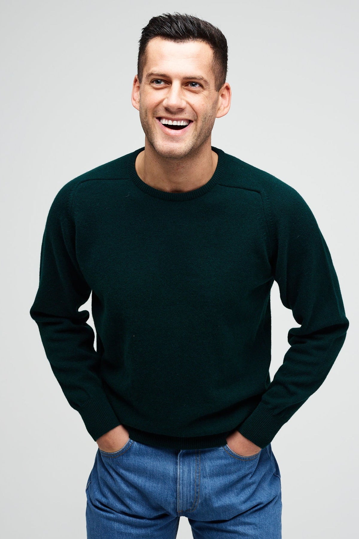 Smiley male wearing lambswool crew neck jumper in bottle green
