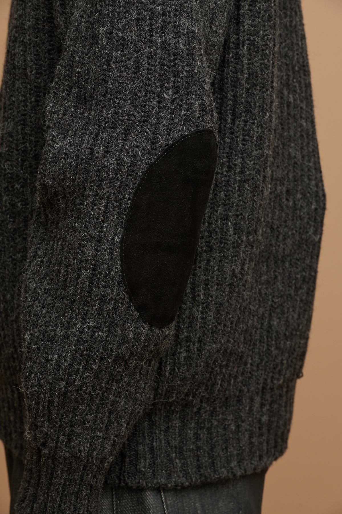 Close up of the side of lambswool fisherman ribbed jumper in charcoal showing suede elbow patch 
