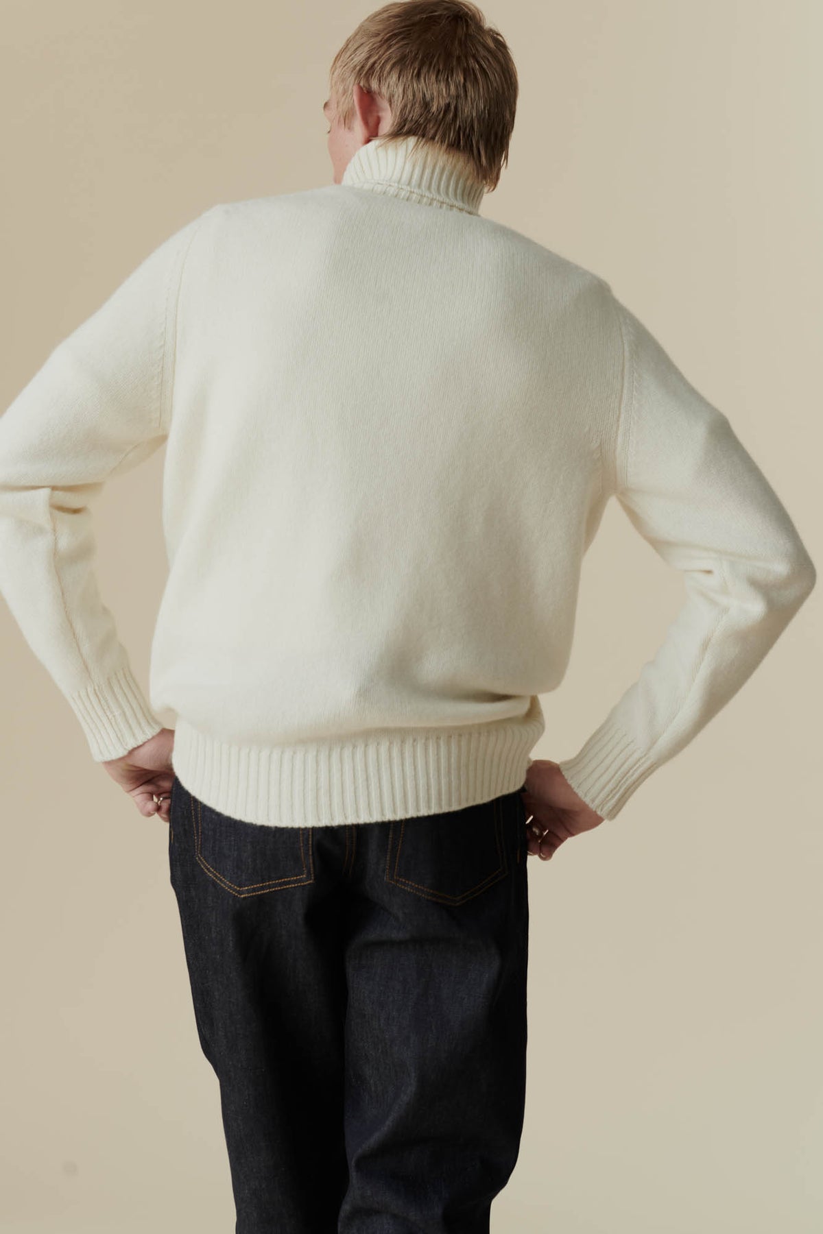 Thigh up shot of white male from behind, wearing lambswool roll neck in ecru