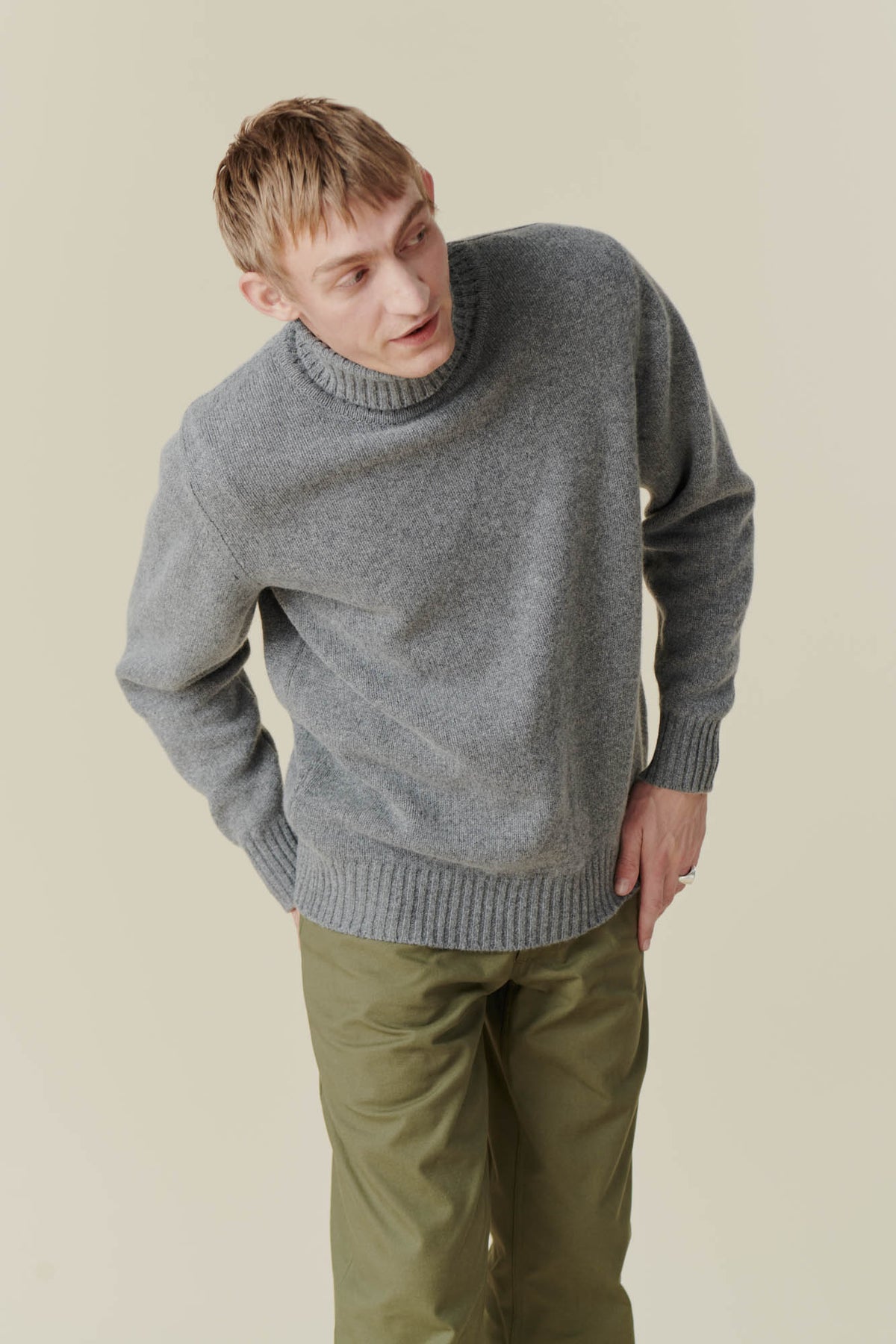 White male wearing grey roll neck jumper and olive cameraman pant