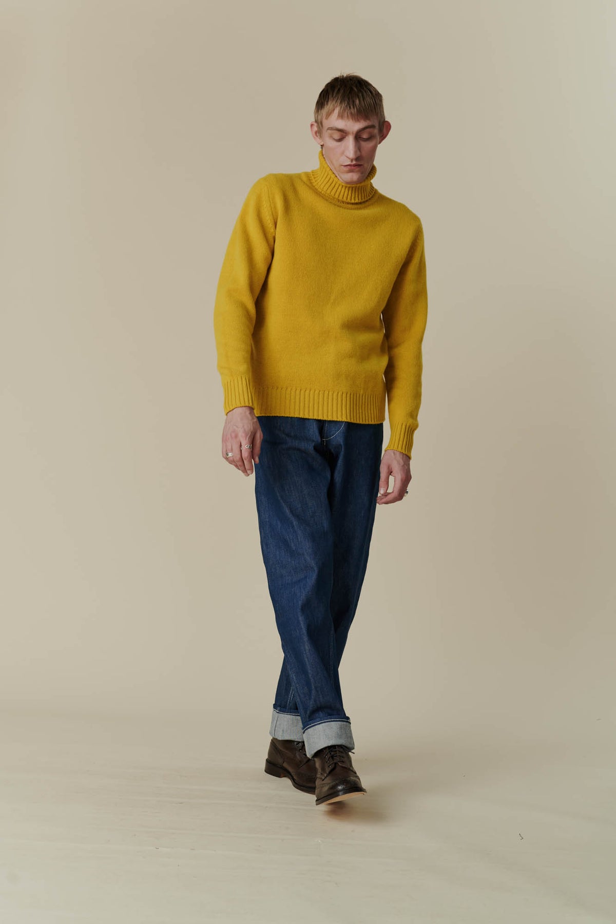Full body image of white male in mustard lambswool roll neck 