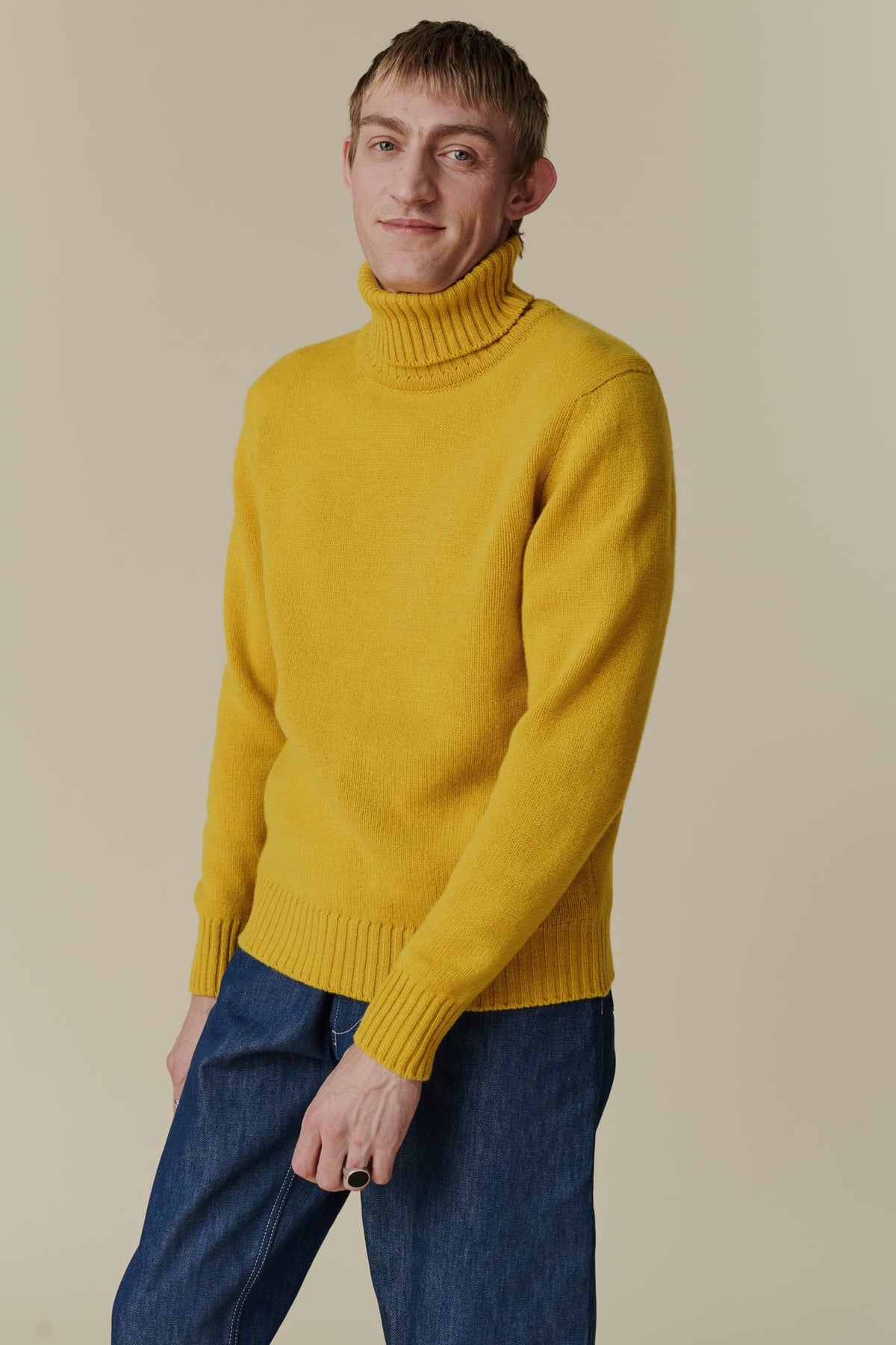 Thigh up image of white male in mustard lambswool roll neck 