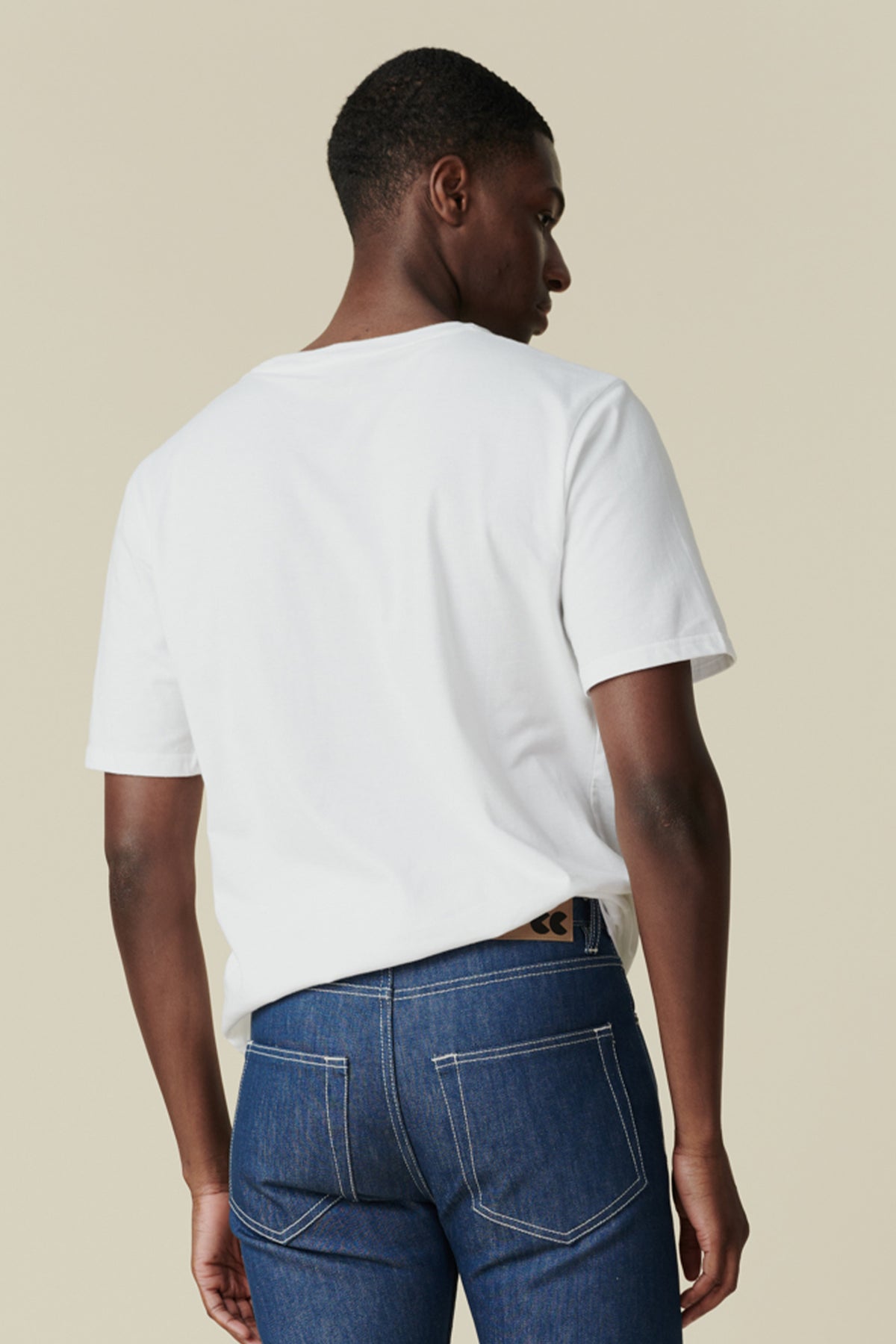 Back of male wearing short sleeve white t shirt paired with blue jeans
